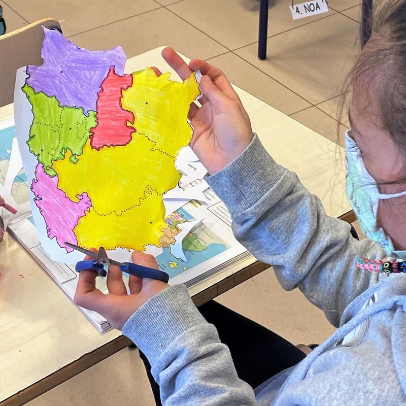 Niños trabajando en equipo a juntar las distintas partes del mapa que han recortado.