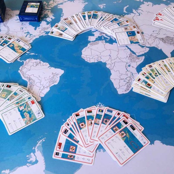 Cards of each continent of the geography game Geocartas mundo on the included giant world map.