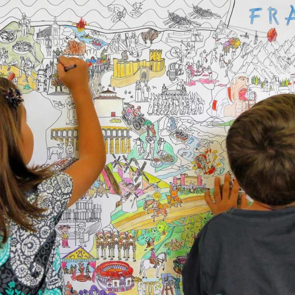 Imagen de 2 niños pintando el mapa de España para colorear en una pared, ella pinta la parte de Galicia